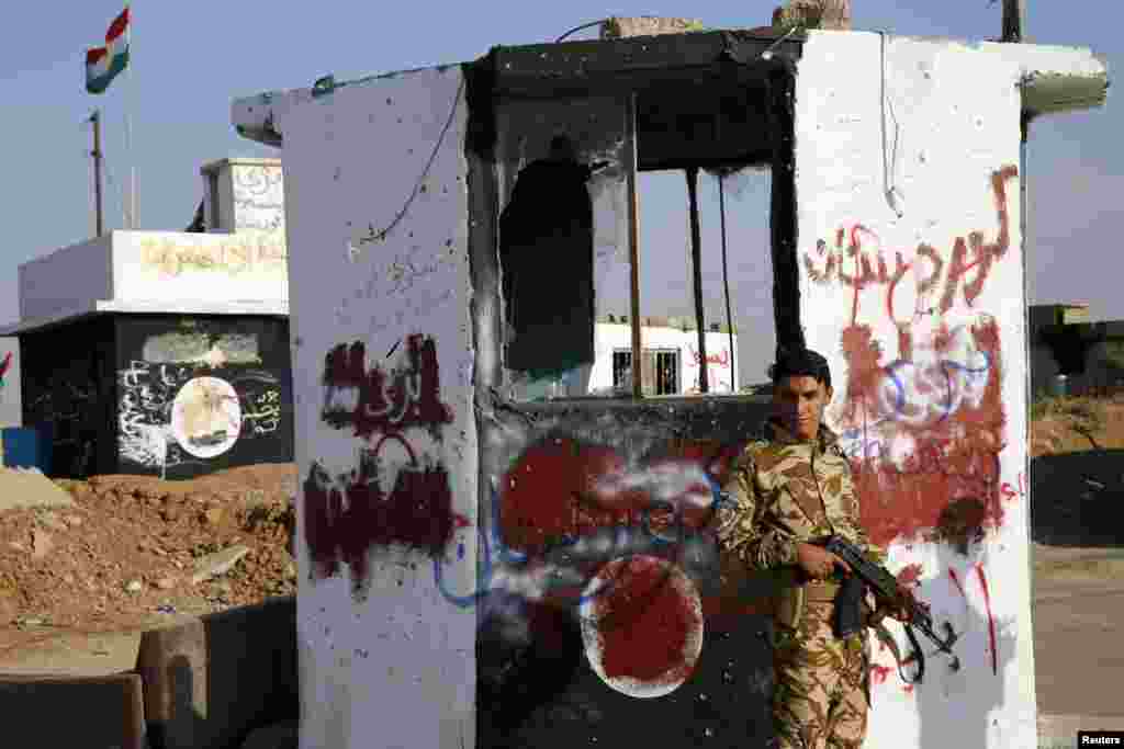 A Kurdish Peshmerga fighter stands at a checkpoint retaken from Islamic State militants in Barznki village in Zummar, near Mosul, Sept. 15, 2014.