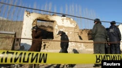 FILE - Security personnel inspect the site of a raid in the village of Besh-Kungei outside Bishkek, Kyrgyzstan, conducted as part of a military operation against suspected Islamist militants, Jan. 6, 2011.