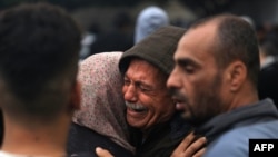Des Palestiniens pleurent leurs proches, tués lors d'une frappe israélienne nocturne contre le camp de réfugiés d'Al-Maghazi, dans le sud de la bande de Gaza, le 25 décembre 2023.