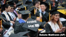 FILE - A graduating student wears a cap reading "hire me," as the City College of New York (CCNY) class of 2016 assemble for commencement, Friday June 3, 2016, in New York.