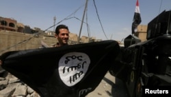 A member of Iraqi Counter Terrorism Service holds an Islamic State militant flag as he celebrates in the Old City of Mosul, Iraq July 9, 2017. 