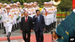 FILE - Cambodian Prime Minister Hun Sen, center right, and his Vietnamese counterpart Nguyen Xuan Phuc, center left, review an honor guard in Hanoi, Dec. 20, 2016. Hun Sen was in Vietnam for a two-day visit aimed at boosting relations between the two Southeast Asian neighbors. 