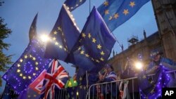 FILE - Pro-European Union protesters wave flags opposite parliament in London.