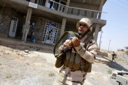 FILE - A Kurdish Peshmerga fighter runs as he and comrades sweep the Bakirta village after Islamic State insurgents withdrew from the town, near Makhmur, south of Irbil, the capital of Iraqi Kurdistan, Aug. 27, 2014.