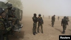 FILE - Cameroonian soldiers from the Rapid Intervention Brigade stand guard amidst dust kicked up by a helicopter in Kolofata, Cameroon, March 16, 2016. 