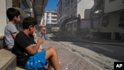Two boys watch an excavator demolish an apartment building in Istanbul, Turkey, Aug. 4, 2023. Six months ago, a 7.8-magnitude earthquake hit the Kahramanmaras and 10 other provinces in southern Turkey. Over 50,000 people died.
