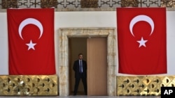 A Turkish parliament security man stands guard next to the broken yellow copper doors laid on the ground at the entrance of the assembly hall at the parliament building which was attacked by the Turkish warplanes during the failed military coup last Friday, in Ankara, Turkey, Tuesday, July 19, 2016.