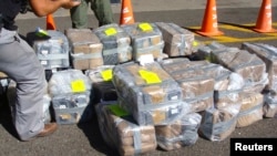 FILE - Costa Rican police officers guard about two tons of cocaine in this handout photo provided by Costa Rica's Ministry of Public Security, Feb. 1, 2012. A cocaine-smuggling operation at the international airport in San Juan, Puerto Rico, has led to 12 suspects being indicted.