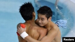 China's Cao Yuan (R) hugs his team mate Zhang Yanquan after their last dive in the men's synchronized 10m platform final during the London 2012 Olympic Games at the Aquatics Centre July 30, 2012. 