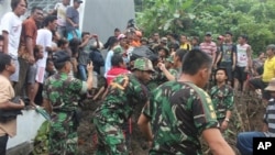 Petugas penyelamat mencari korban tanah longsor di Manado, Sulawesi Utara, Minggu (17/2). (Foto: AP)