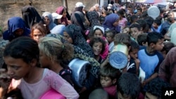 FILE - Palestinians line up for food distribution in Deir al-Balah, Gaza Strip, Oct. 17, 2024.