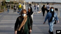 People wearing face masks exercise on the shore of an artificial lake, in Western Tehran, Iran, Sunday, March 15, 2020. 