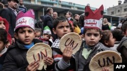 Palestinian children hold bread patties during a protest against aid cuts, outside the United Nations' offices in Khan Yunis in the southern Gaza Strip on January 28, 2018.