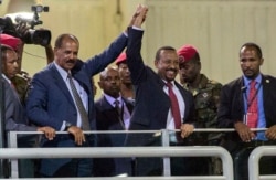 FILE - Eritrean President Isaias Afwerki, second left, and Ethiopia's Prime Minister Abiy Ahmed, center, hold hands as they wave at the crowds in Addis Ababa, Ethiopia, July 15, 2018.