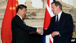 资料照片: 2015年10月21日，英国首相戴维·卡梅伦(右)在伦敦中英商业峰会上与中国国家主席习近平握手