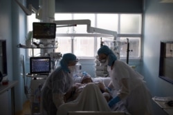 FILE - Healthcare workers assist a COVID-19 patient in the intensive care unit at the Joseph Imbert Hospital Center in Arles, southern France, April 5, 2020.