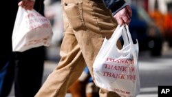FILE - Pedestrians carry plastic bags in Philadelphia, March 3, 2021. Giving out single-use plastic bags in the city became illegal this fall, but penalties don’t start until April 1.