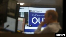 A traders works as EU Referendum results come in on a giant screen behind, in London, Britain, June 24, 2016.