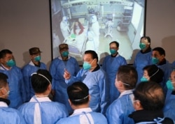 FILE - Chinese Premier Li Keqiang wearing a mask and protective suit speaks to medical workers as he visits the Jinyintan hospital where patients of the new coronavirus are being treated, in Wuhan, Jan. 27, 2020.