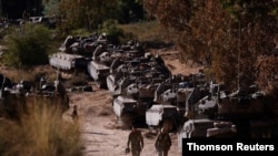 Israeli soldiers walk next to tanks near the border between Israel and the Gaza Strip, on its Israeli side May 15, 2021.