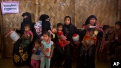 Rohingya Muslim refugee women with their children wait at a nutrition center to collect the diet for their children at Balukhali refugee camp 50 kilometres (32 miles) from, Cox's Bazar, Bangladesh, Jan. 23, 2018. 