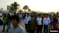 FILE - Migrant workers walk on the corniche in Doha, Qatar April 14, 2017. 