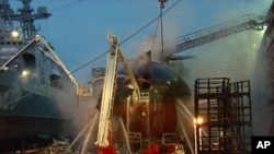 In this video image from Ru-RTR Russian state television channel, firefighters spray water on the Yekaterinburg nuclear submarine in a dock at the Roslyakovo shipyard in the Murmansk region, Russia. A fire that erupted while the Yekaterinburg was in dry-d