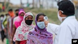 A migrant worker gets her temperature checked before being allowed to board a train tomorrow to head to her home state, in Jammu, India, June.11, 2020. 