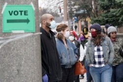 Voters masked against coronavirus line up at Riverside High School for Wisconsin's primary election, in Milwaukee, April 7, 2020.