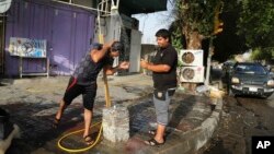 People cool themselves with water in central Baghdad, Iraq, July 16, 2015. The government declared Thursday an official holiday due to scorching temperatures. 