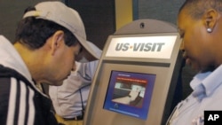 FILE - Department of Homeland Security official (r) assist a passenger (l) as he scans his fingerprint on a machine, part of the exit process at Hartsfield-Jackson Atlanta International Airport in Atlanta.