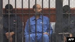 FILE - Saif al-Islam Gadhafi in the accused cell as he stands trial for illegally trying communicating with the outside world in June of 2012, Zintan, Libya, May 2, 2013.
