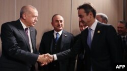 A Turkish Presidential Press photos shows Turkey's President Recep Tayyip Erdogan, left, and Greek Prime Minister Kyriakos Mitsotakis shaking hands during a meeting at the NATO summit in London, Dec. 4, 2019.