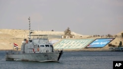 FILE - A cargo ship sails through the town of Ismailia, Egypt, March 30, 2021, as traffic resumed through the Suez Canal after it was blocked by a massive ship that had been stuck sideways for nearly a week.