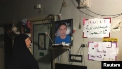 FILE - Lotfy Ibrahim’s mother, Tahany, looks at a photograph of her son at home in Kafr al-Sheikh, Egypt, Jan. 13, 2019. 