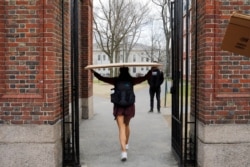 FILE - A student carries a box to her dorm at Harvard University, after the school asked its students not to return to campus after Spring Break and said it would move to virtual instruction, in Cambridge, Massachusetts, March 10, 2020.