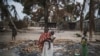 A woman holds her child while standing in a burned out area in the attacked village of Aldeia da Paz outside Macomia in Cabo Delgado Province, in Mozambique, on Aug. 24, 2019.