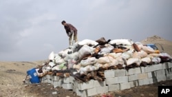FILE - An Afghan man prepares to set narcotics on fire on the outskirts of Kabul, Oct. 29, 2014.