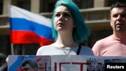 A Russian opposition supporter holds a banner with pictures of slain Kremlin critic Boris Nemtsov during a rally in Moscow, Russia, May 6, 2017.