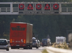FILE - Cars pass a hazard warning that reads, 'Caution, danger of heat damage' on the A81 highway near Sindelfingen, Germany, August 8, 2015.