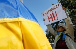 A woman attends a rally against the approval of a local election accord, in Kyiv, Ukraine, Oct. 2, 2019. Her sign reads: "No capitulation!"