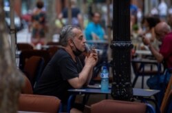 A man smokes on a terrace bar in Barcelona, Spain, Aug. 14, 2020. Spanish Health Minister Salvador Illa announced a range of new nationwide restrictions to help fight a surge in COVID-19 cases.