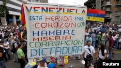 FILE - Opposition supporters rally against President Nicolas Maduro carrying a sign that reads "Venezuela is wounded in the heart with hunger, misery, corruption and dictatorship," in Caracas, Venezuela, May 10, 2017.