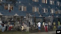 Somali security forces and civilians gather outside the Weheliye hotel after it was stormed by militants in Mogadishu, Somalia, July 10, 2015. 