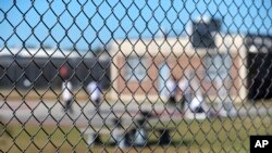FILE - Detainees sit in a yard during a media tour inside the Winn Correctional Center in Winnfield, La. 