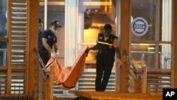 Police officers carry a body bag from a bus stop where a suspected suicide bombing occurred in Jakarta, Indonesia, May 25, 2017.