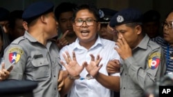 Reuters journalist Wa Lone, center, talks to journalists as he is escorted by police to leave a court in Yangon, Myanmar, Sept. 3, 2018.