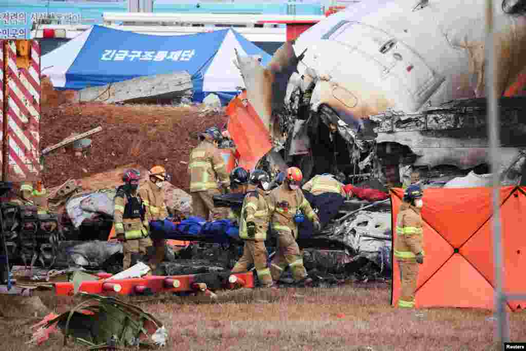 Firefighters carry the body of a passenger from the wreckage of a&nbsp;Jeju aircraft that crashed after it went off the runway at Muan International Airport, in Muan, South Korea, Dec. 29, 2024.