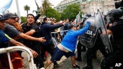 Soccer fans waiting to see Diego Maradona lying in state clash with police outside the presidential palace in Buenos Aires, Argentina, Nov. 26, 2020.