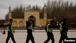 FILE - Police walk in front of the Id Kah Mosque in the old city of Kashgar, Xinjiang Uighur Autonomous Region, China, March 22, 2017.